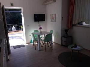 - un salon avec une table et des chaises vertes dans l'établissement Apartments Viki, à Trogir