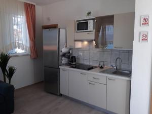 La cuisine est équipée d'un réfrigérateur en acier inoxydable et d'un évier. dans l'établissement Apartments Viki, à Trogir