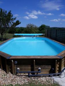 a swimming pool with a wooden deck and a blue pool at Hôtes de l'Isle in Saint-Médard-de-Mussidan