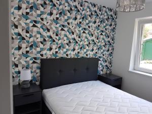 ein Schlafzimmer mit einem Bett und einer geometrischen Wand in der Unterkunft Le petit Wachipré in Rochehaut