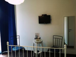 a room with two chairs and a table and a tv on the wall at Zenzero & Cannella Boutique Rooms in Trieste