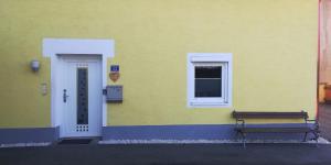 un edificio giallo con una panchina accanto a una porta di Home Sweet Home a Reichersdorf