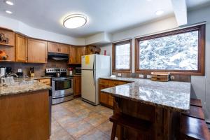 a kitchen with wooden cabinets and a white refrigerator at Meadow Creek Townhome by Vail Realty in Vail