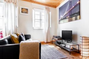 a living room with a black couch and a tv at InLoveApartments - Duplex at Alfama in Lisbon