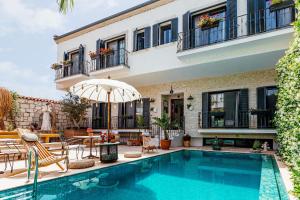 a swimming pool in front of a house with an umbrella at Alachi Hotel in Alacati