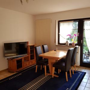 uma sala de jantar com uma mesa e cadeiras e uma televisão em Haus Waldeck em Dasburg