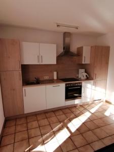 uma cozinha com armários brancos e piso em azulejo em Haus Waldeck em Dasburg