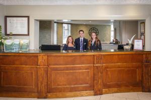 a man and three women standing at a reception desk at The Maids Head Hotel in Norwich