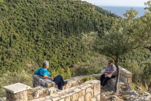 a group of people sitting on a wall looking at a mountain at Trisilio in Kardamyli