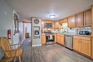 a kitchen with wooden cabinets and stainless steel appliances at Rustic and Modern Russell Cabin with Grill and Deck in Russell