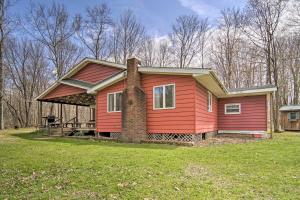 ein rotes Haus mit einem gemauerten Kamin im Hof in der Unterkunft Rustic and Modern Russell Cabin with Grill and Deck in Russell