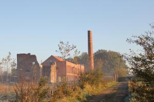 a train is traveling past an old factory at B&B Amuse-Couche in Hasselt