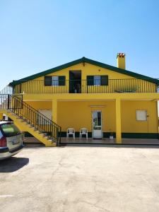 a yellow house with a balcony and two chairs at 3 bedrooms house with enclosed garden and wifi at Sobral de Monte Agraco in Sobral de Monte Agraço