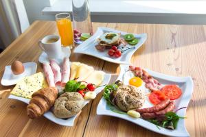 two plates of food on a wooden table with breakfast foods at Willa Karmazyn in Międzyzdroje