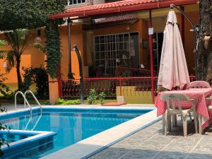 a pool with a table and umbrella next to a house at Hotel Paraiso Huasteco in Tamazunchale