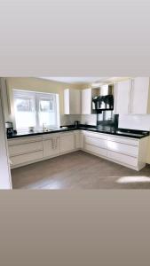 a kitchen with white cabinets and black counter tops at Stadtvilla Lingen in Lingen