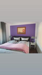 ein großes Bett mit einem lila Kopfteil in einem Schlafzimmer in der Unterkunft Stadtvilla Lingen in Lingen