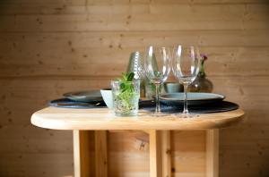 a table with three wine glasses and plates on it at Kampinastaete, hippe cottages midden in natuurgebied de Kampina Oisterwijk in Oisterwijk