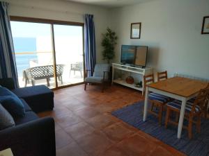 a living room with a couch and a table with a television at Ribalta Beach Houses in Ericeira