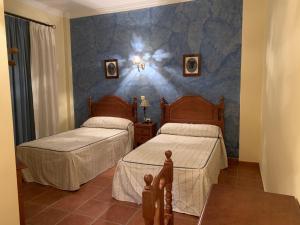 a bedroom with two beds and a blue wall at Habitaciones rurales Venta Pedro in Casabermeja