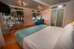 een slaapkamer met een groot wit bed en een televisie bij Hotel Reina del Mar By Dorado in San Andrés