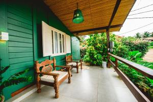 a green house with two benches on the porch at Pousada Verdes Mares in Fernando de Noronha