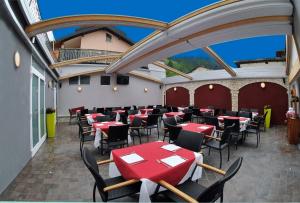 un restaurant avec des tables et des chaises rouges sur une terrasse dans l'établissement Albergo Alla Torre, à Caldonazzo