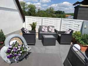 a patio with chairs and a table and flowers at Apartment Elegance in Höheischweiler