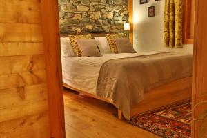 ein Schlafzimmer mit einem Bett und einer Steinmauer in der Unterkunft Chalet Mavambo in Le Châble