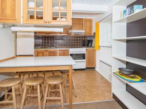 a kitchen with wooden cabinets and a counter with stools at 6 person holiday home in R m in Rømø Kirkeby