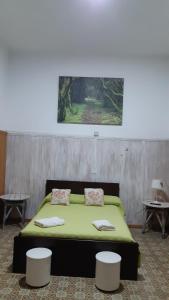 una camera da letto con un letto con lenzuola verdi e due sgabelli di Casa rural el Burro para grupos ad Agüimes