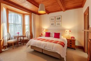 a bedroom with a bed with red pillows and a table at French Bay House in Akaroa