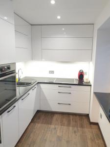 a kitchen with white cabinets and a wooden floor at MARBEO 5 Star Luxury Suites - Siena in Liepāja