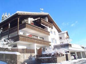 a white building with balconies and snow on the ground at Haus Elli in Nova Ponente