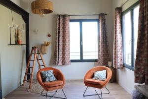 two chairs and a ladder in a room with windows at Gite Aigues Vives in Montpeyroux