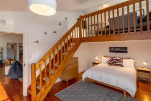 1 dormitorio con 1 cama y escalera de madera en The Wine Shed, en Martinborough