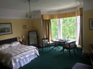 um quarto com uma cama, uma mesa e uma janela em Kilmorie House em Elgin