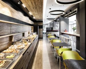 a restaurant with a long counter with yellow chairs at Best Western Hotel Corsi in Torrimpietra