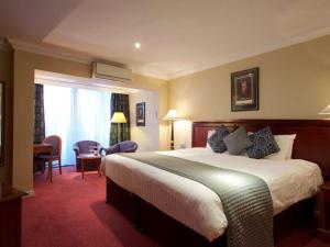 a hotel room with a large bed and a desk at Derby Mickleover Hotel, BW Signature Collection in Derby