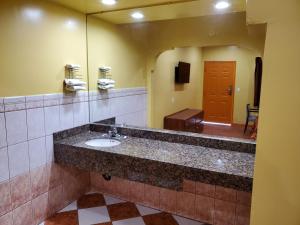 a bathroom with a sink and a mirror at Sunrise Inn in South Gate
