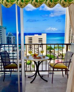 balcón con mesa, sillas y vistas al océano en Jenny's Cottage Waikiki en Honolulu