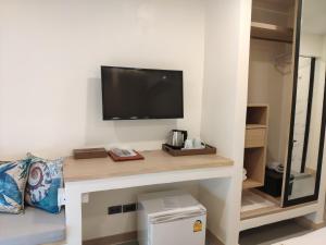 a room with a desk with a television on a wall at Stay Inn Nathon Samui in Nathon