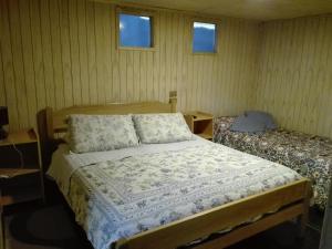 a bedroom with a bed and two tables and two windows at Hospedaje Los Calafates in Ancud