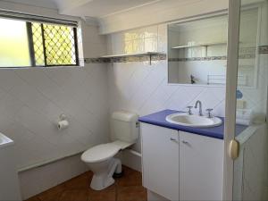 a white bathroom with a toilet and a sink at Harbour Side Resort in Gold Coast