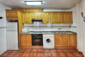 a kitchen with wooden cabinets and a washing machine at Apartamentos Petronilla in Benasque