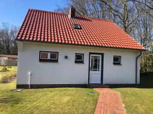 una pequeña casa blanca con techo naranja en Haus 1 en Wyk auf Föhr