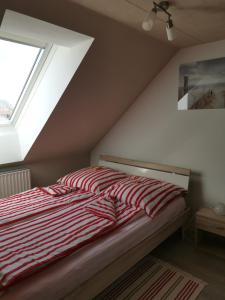 a bed with a red and white striped comforter and a window at Susan's ole Schoolhus in Fehmarn