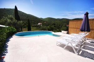 een zwembad met twee stoelen en een parasol bij Cosy Apartment in Žrnovo - 30 sqm with Shared Pool in Korčula