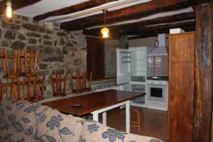 cocina con mesa, sillas y pared de piedra en Casa Rural Las Machorras I y II, en Bárcenas