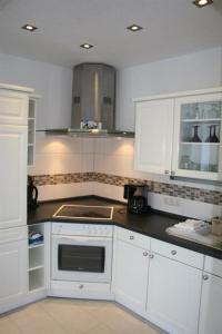 uma cozinha com armários brancos e um forno com placa de fogão em Ferienhaus Grimm em Friedrichsbrunn